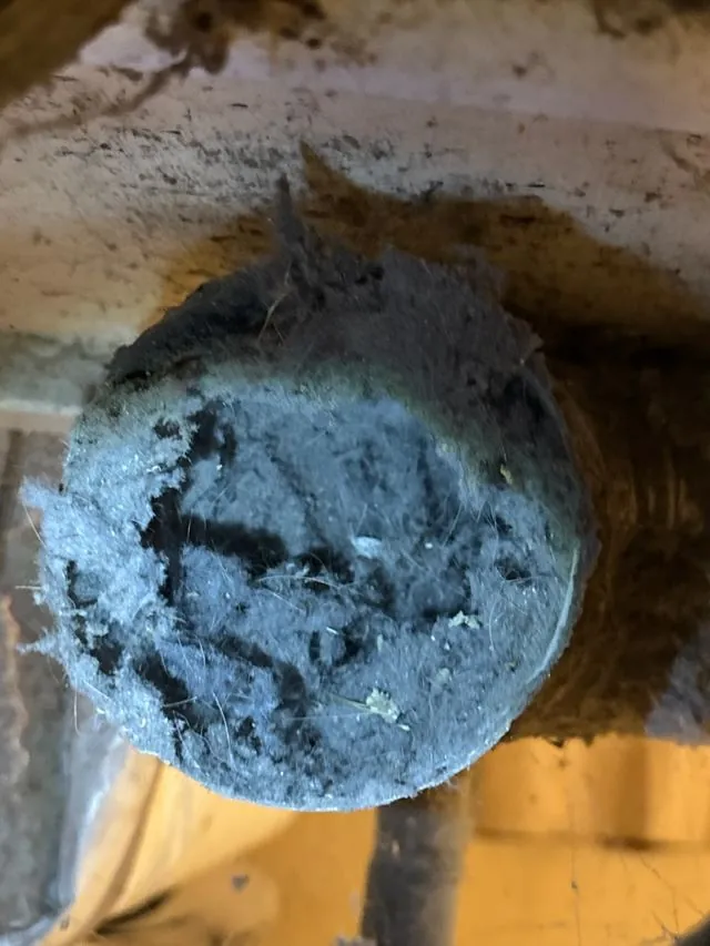 A thick plug of compacted lint blocking a dryer vent duct